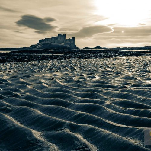 Bambrugh castle across waves of rippled sand