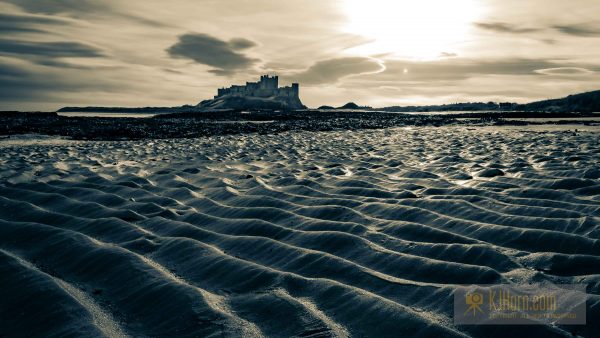 Bambrugh castle across waves of rippled sand